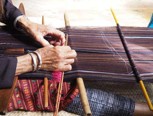Hands weaving cashmere on a traditional wooden loom